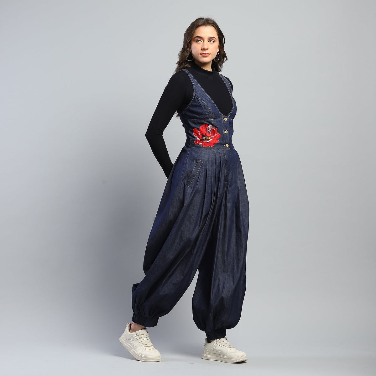 Woman wearing a navy blue jumpsuit with a red floral design on a gray background