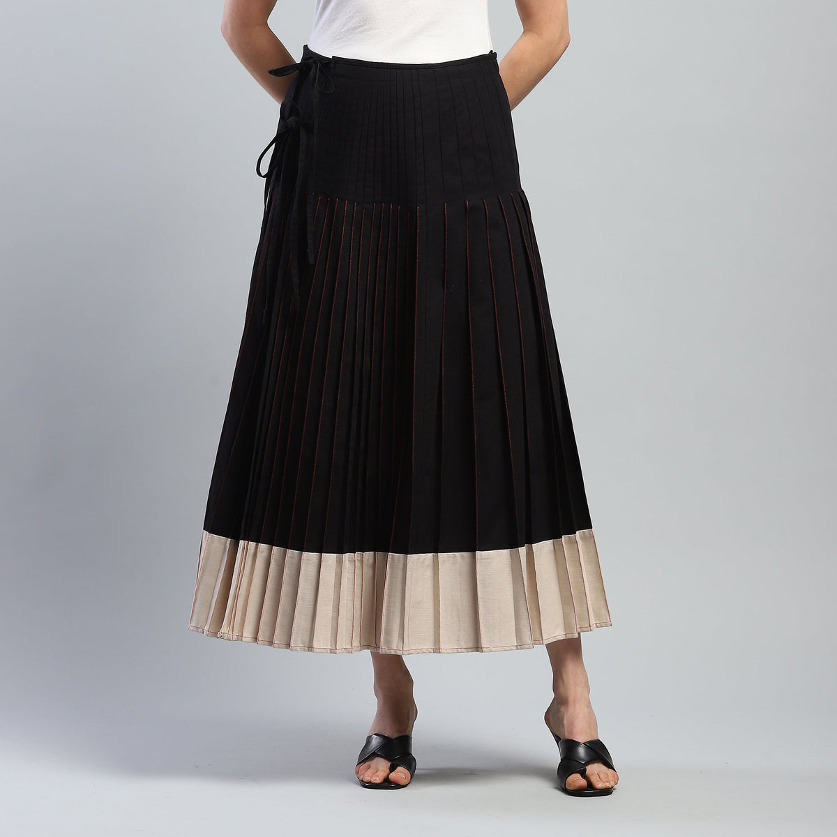 Black pleated skirt with beige hem on a gray background