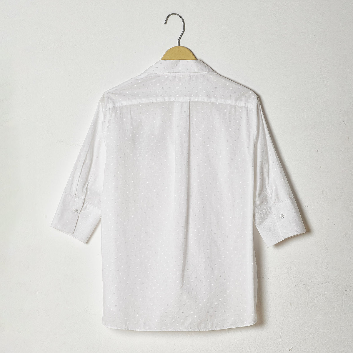 White shirt on a hanger against a white background