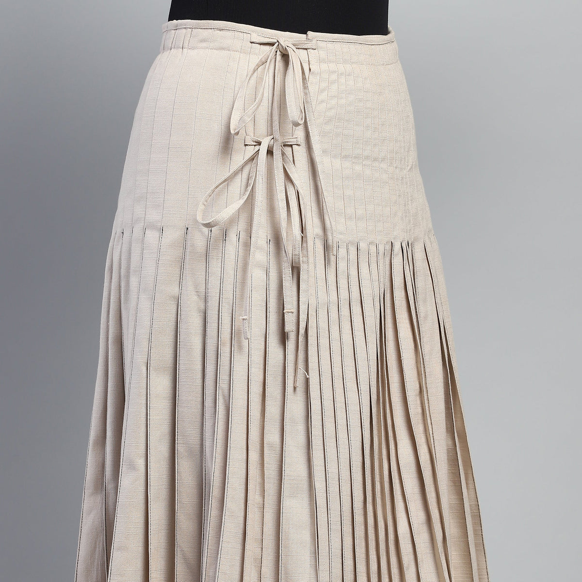 Beige pleated skirt with a tie waist on a gray background