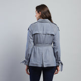 Woman wearing a gray jacket with a belt on a gray background