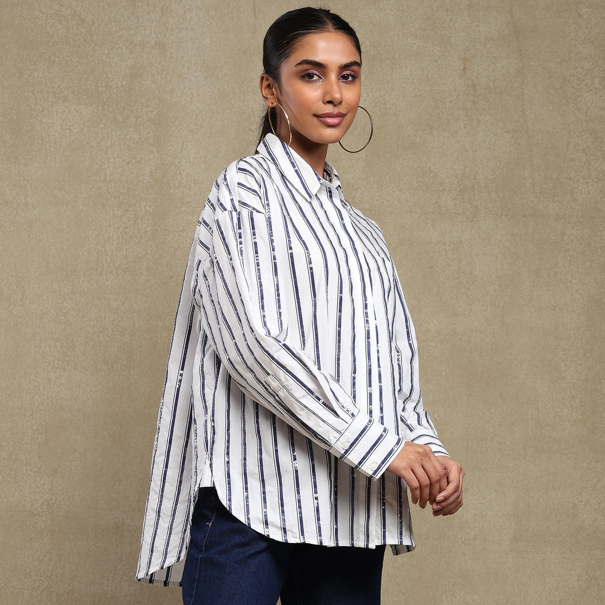Woman wearing a white and black striped shirt against a beige background