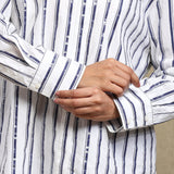 Close-up of a person wearing a white shirt with blue vertical stripes, adjusting the cuff.