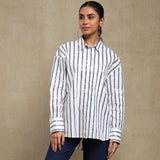 Woman wearing a white and black striped shirt against a beige background