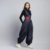 Woman wearing a navy blue jumpsuit with a red floral design on a gray background