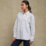 Woman wearing a white shirt with black vertical stripes against a beige background