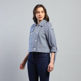 Woman wearing a light blue denim jacket on a gray background