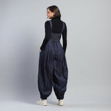 Person wearing a dark blue jumpsuit with suspenders on a plain background
