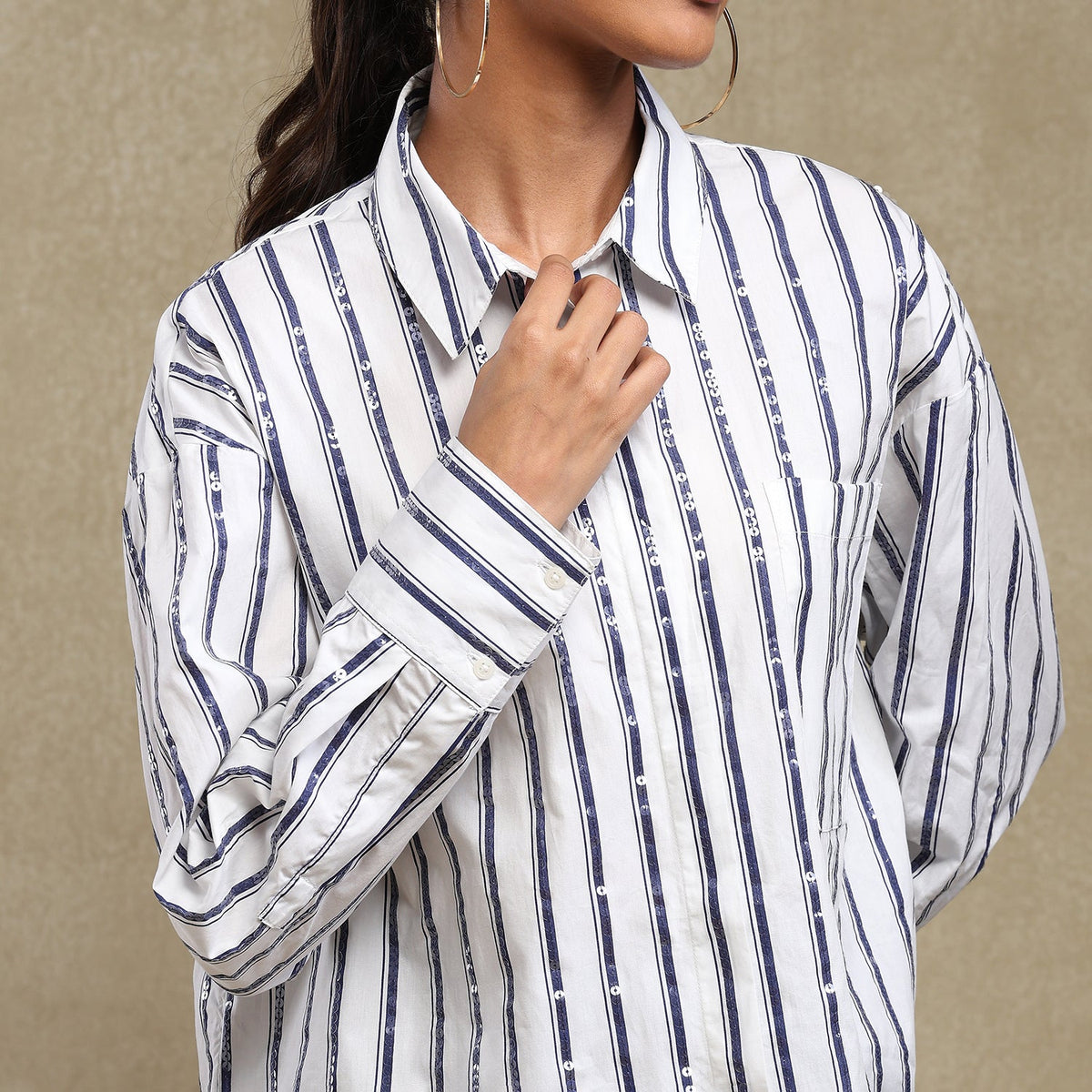 Person wearing a white shirt with blue stripes against a beige background
