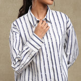 Person wearing a white shirt with blue stripes against a beige background