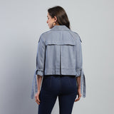 Woman wearing a light blue denim jacket on a gray background