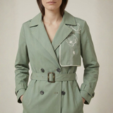 Green trench coat with floral embroidery on a neutral background